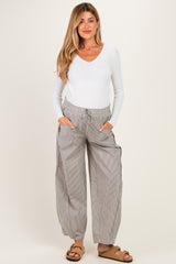 woman wearing a white long sleeve v-neck maternity top and gray striped wide-leg maternity pants with pockets
