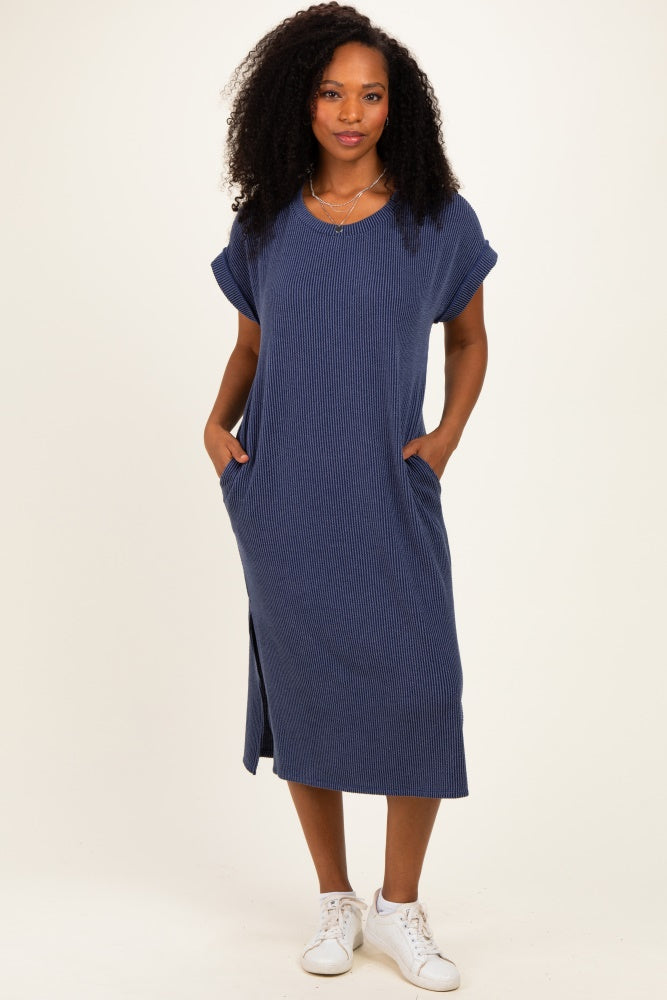 woman wearing a navy blue midi dress with rolled sleeves and side pockets, standing against a neutral background