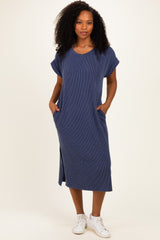 woman wearing a navy blue midi dress with rolled sleeves and side pockets, standing against a neutral background