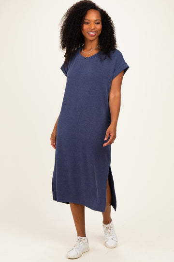 woman wearing a navy blue ribbed midi dress with short sleeves and side slits, styled with white sneakers
