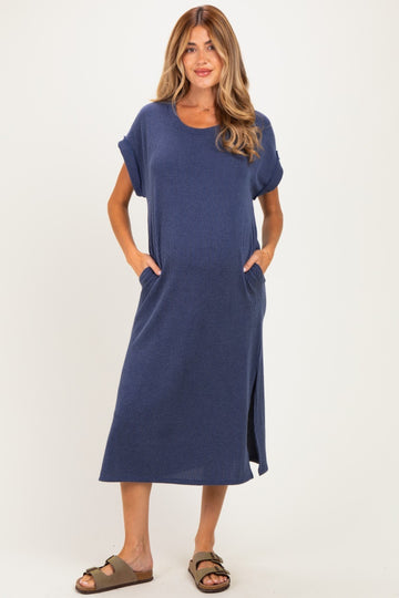 woman wearing a navy striped midi maternity dress with short sleeves and pockets, no visible baby bump