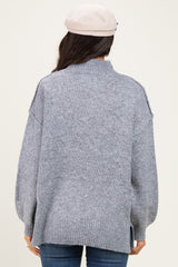 woman wearing a gray oversized turtleneck sweater with side slits and relaxed fit from the back