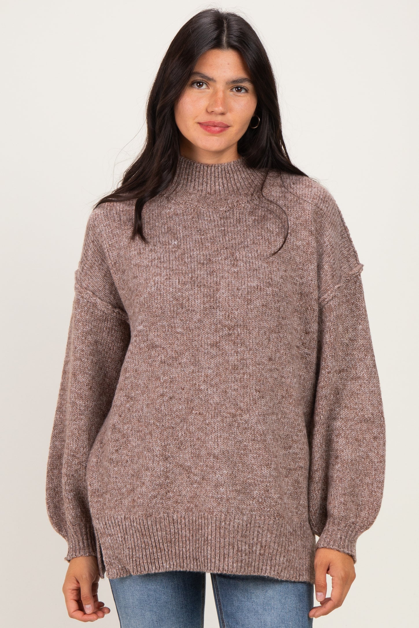 woman wearing a taupe oversized knit sweater with balloon sleeves and a high neckline