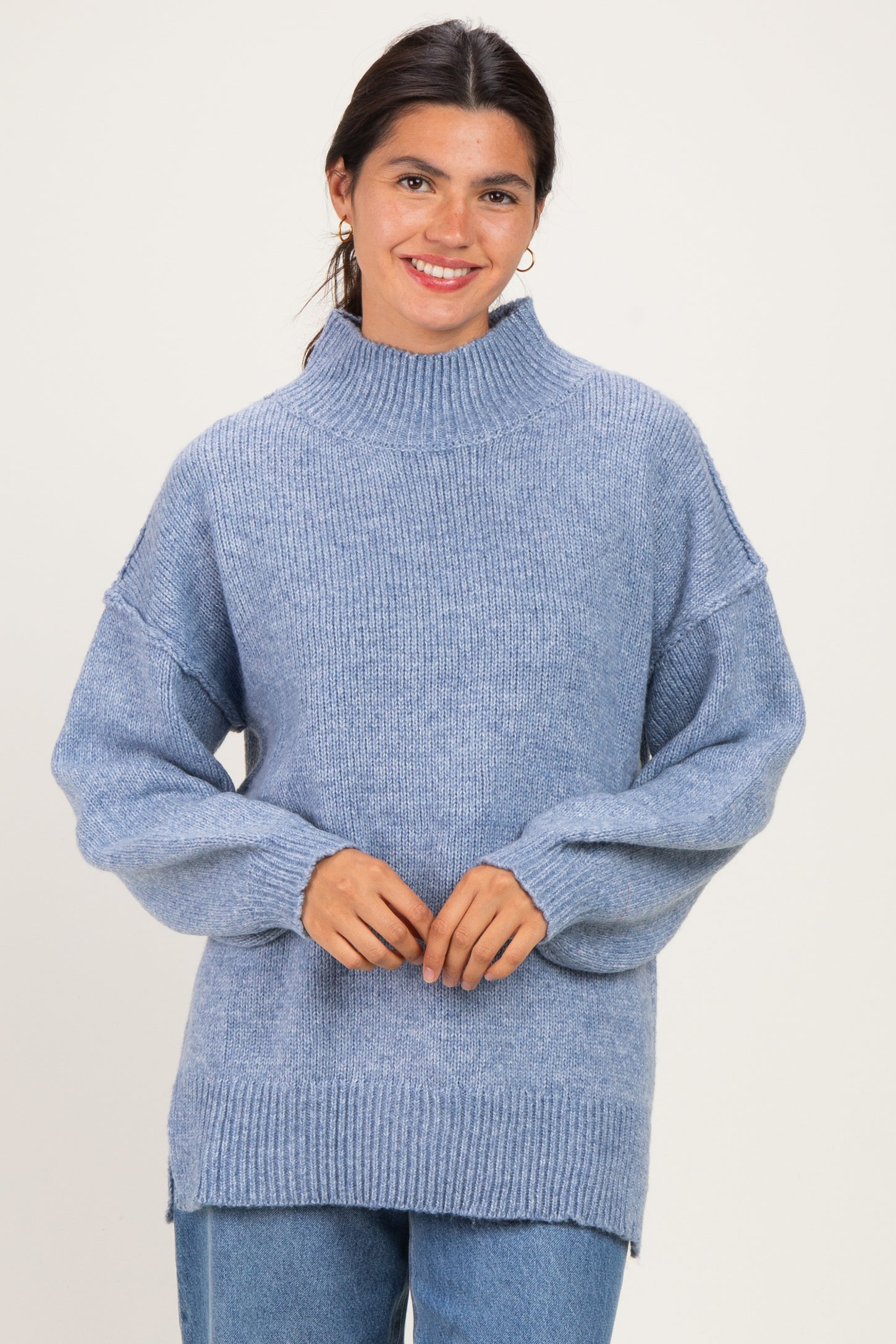 woman wearing a light blue oversized knit sweater with a high neckline and loose sleeves