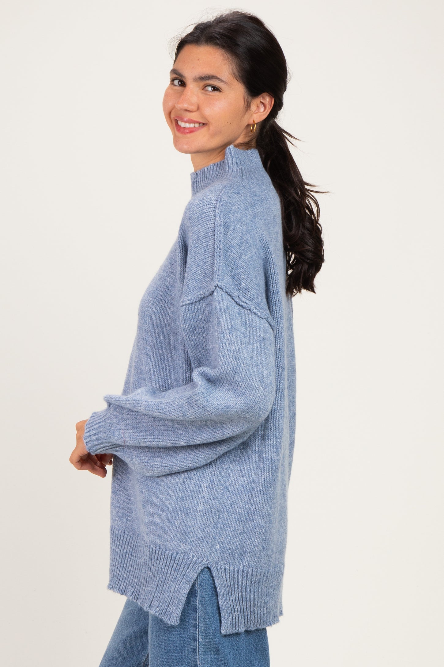 woman wearing a light blue oversized knit sweater with side slits and long sleeves