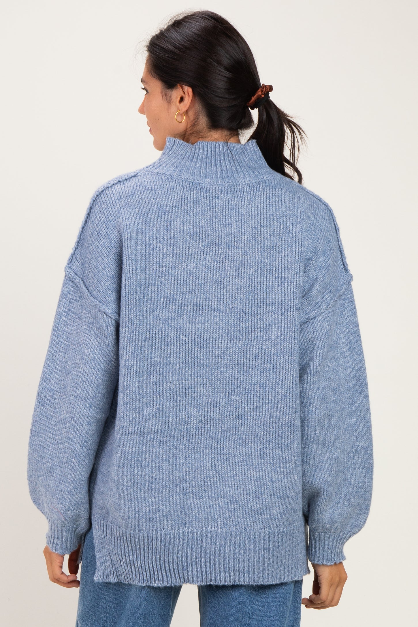 woman wearing a light blue oversized sweater with a high neck and drop shoulder sleeves