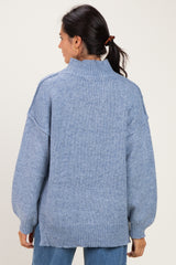 woman wearing a light blue oversized sweater with a high neck and drop shoulder sleeves