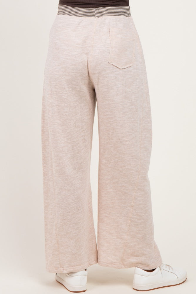woman wearing light taupe maternity wide-leg pants, view from the back, paired with white sneakers