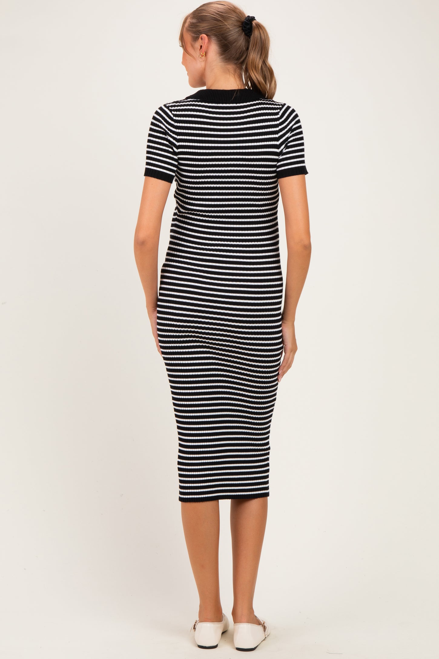 woman wearing a black and white striped maternity dress, seen from the back