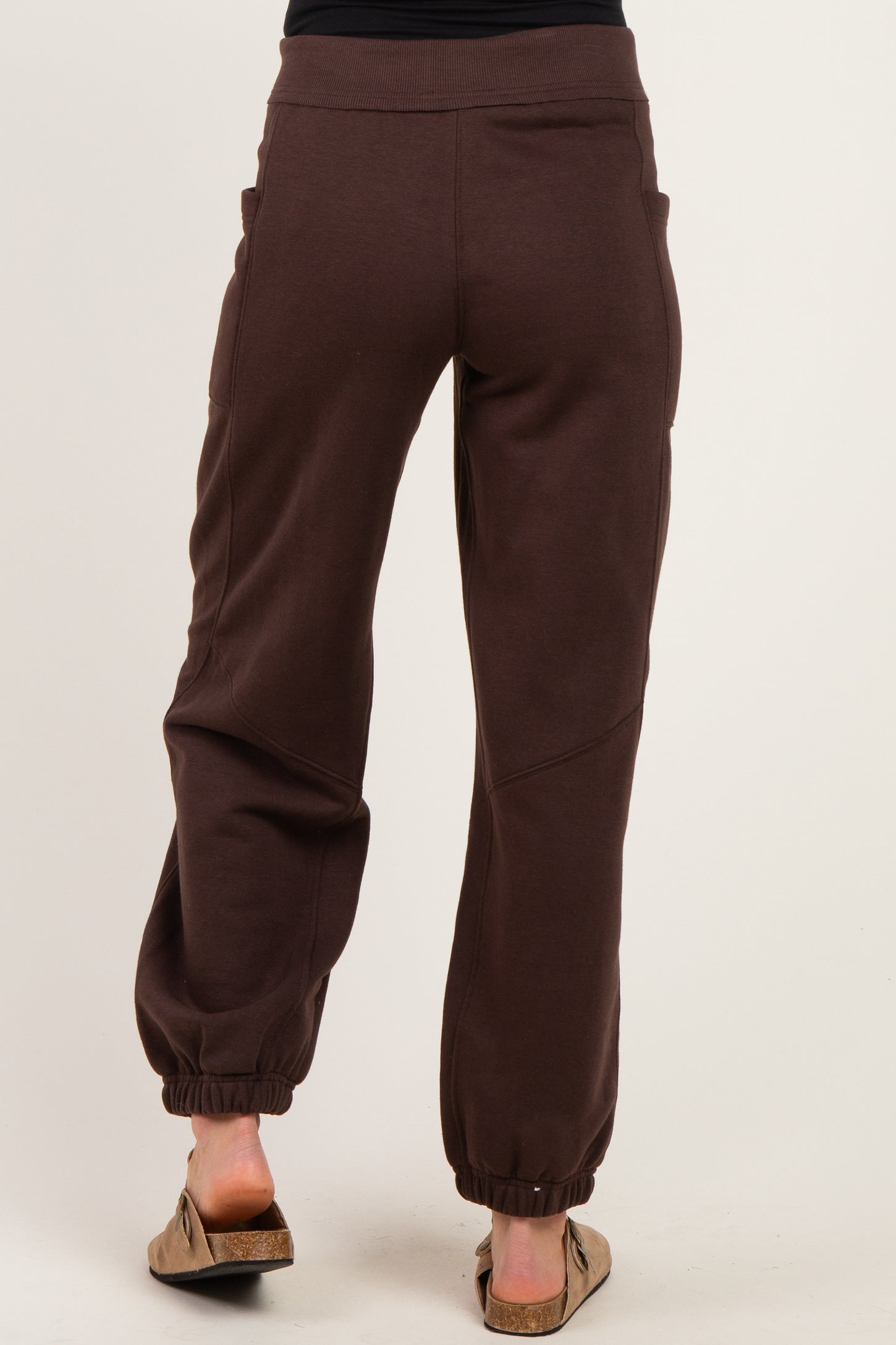 woman wearing brown maternity joggers with pockets, showing the back view and elastic ankle cuffs