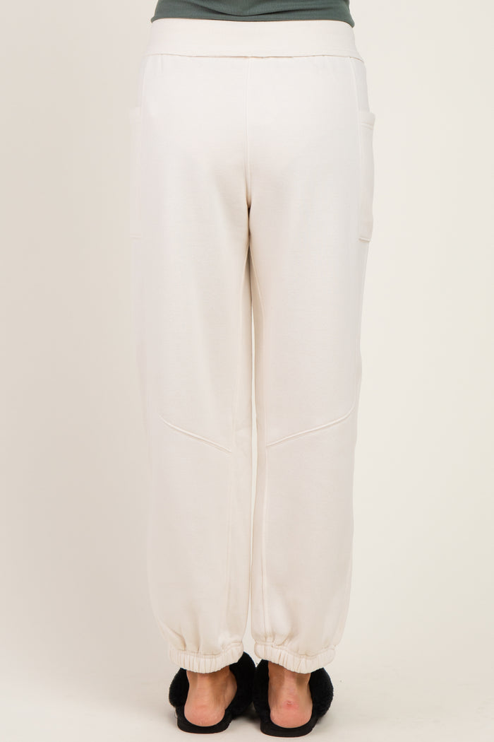woman wearing cream colored maternity jogger pants with elastic cuffs and side pockets, viewed from the back
