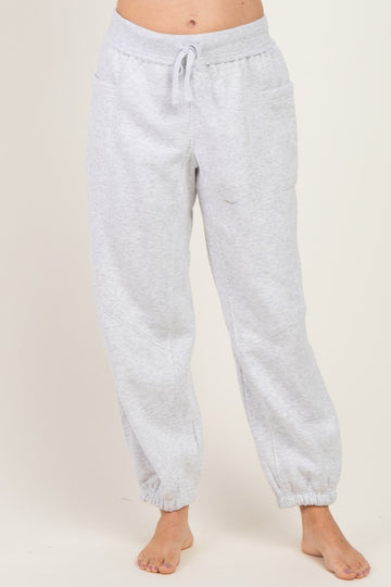 woman wearing light grey sweatpants with elastic cuffs and adjustable drawstring waistband, standing barefoot