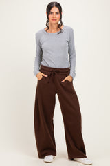 woman wearing a light gray long sleeve top and brown wide-leg sweatpants with pockets
