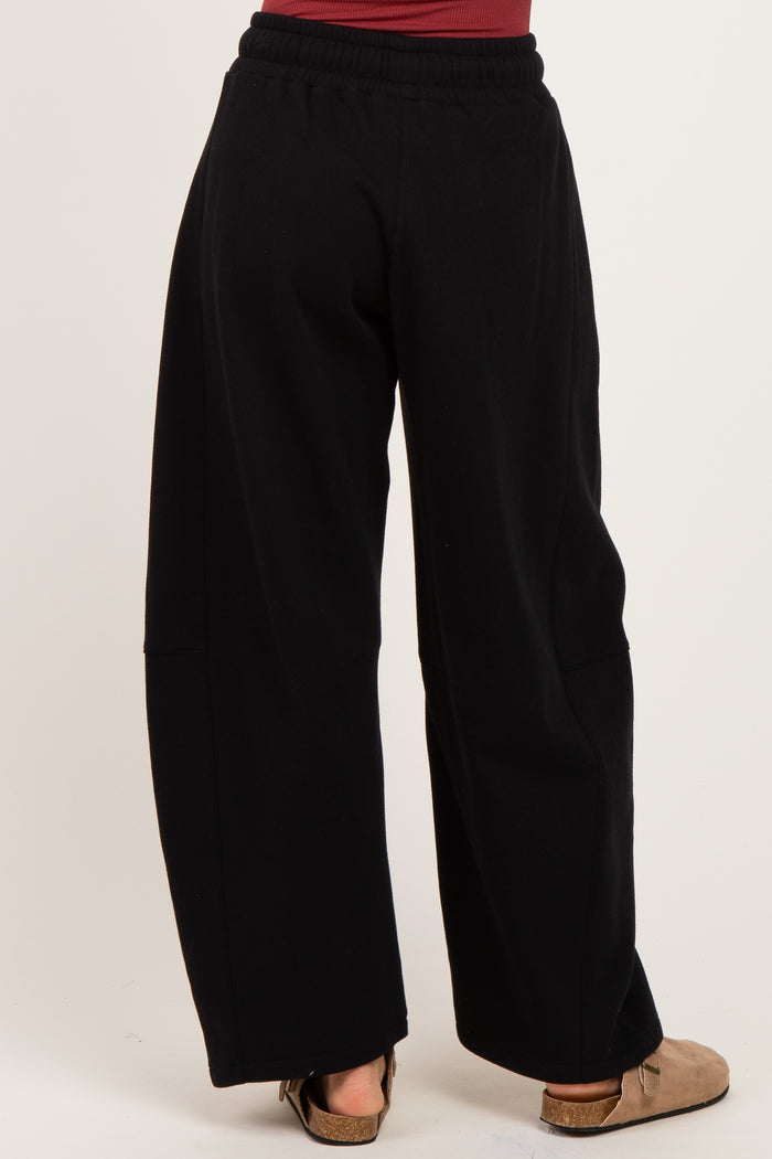 woman wearing black wide-leg sweatpants, shown from the back with a relaxed fit and elastic waistband