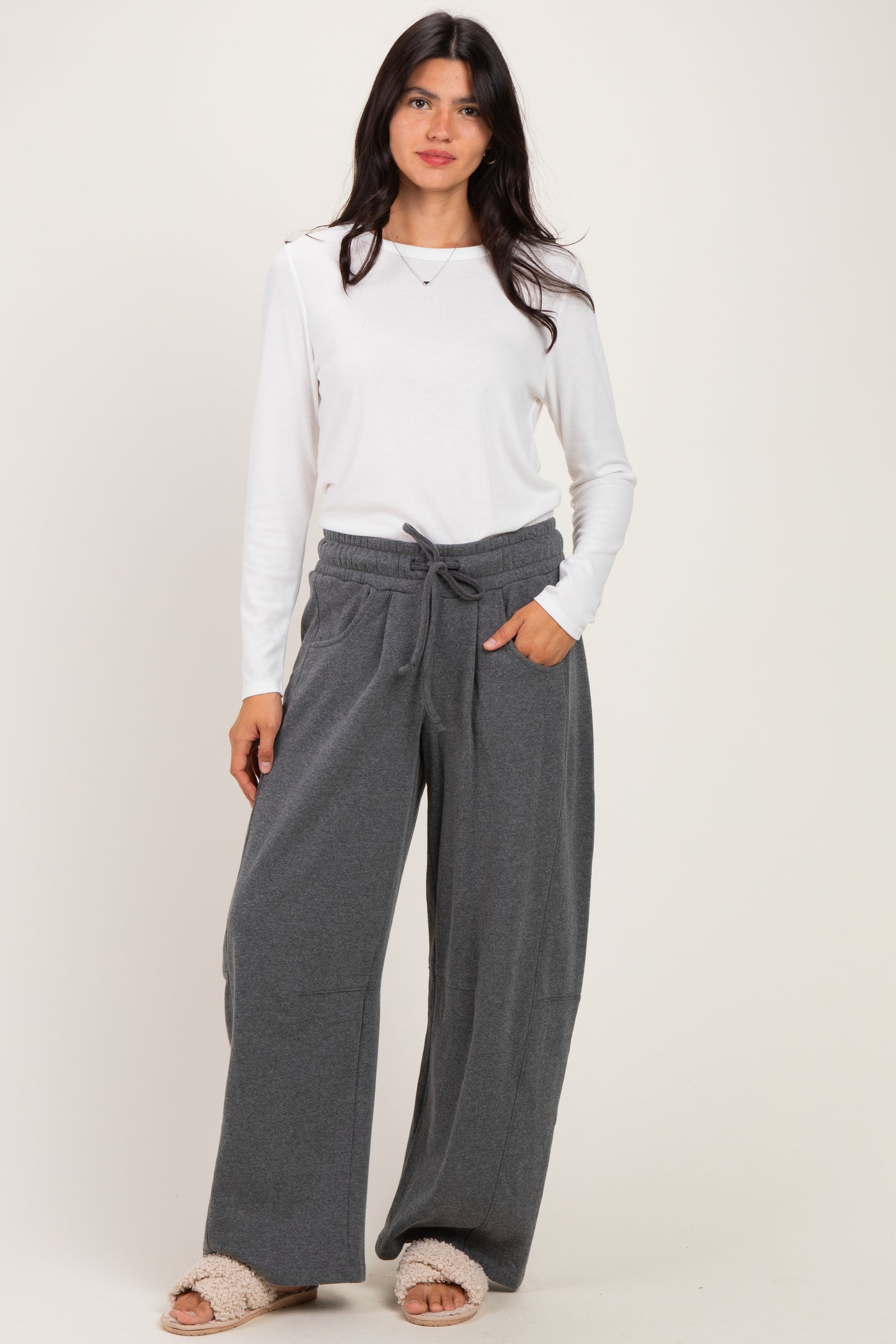 woman wearing a white long sleeve ribbed top and gray wide leg lounge pants with a drawstring waist