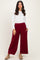 woman wearing a white long sleeve top and burgundy wide-leg pants with side pockets