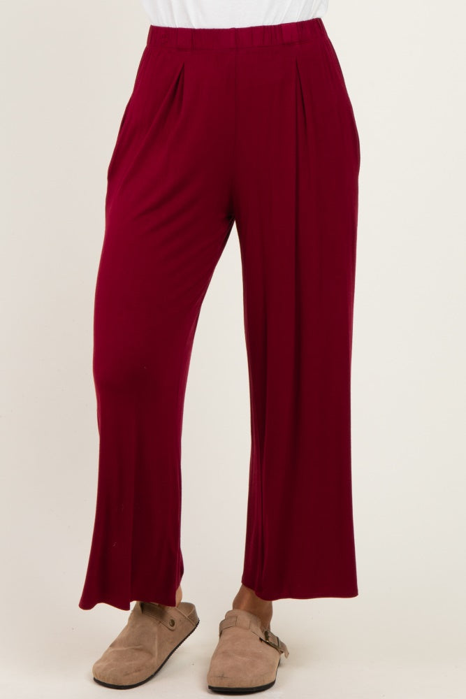 woman wearing burgundy pleated wide leg pants with a relaxed fit and side pockets