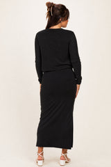 woman wearing a black long sleeve maternity top and matching maxi skirt, showing a pregnant belly from the back