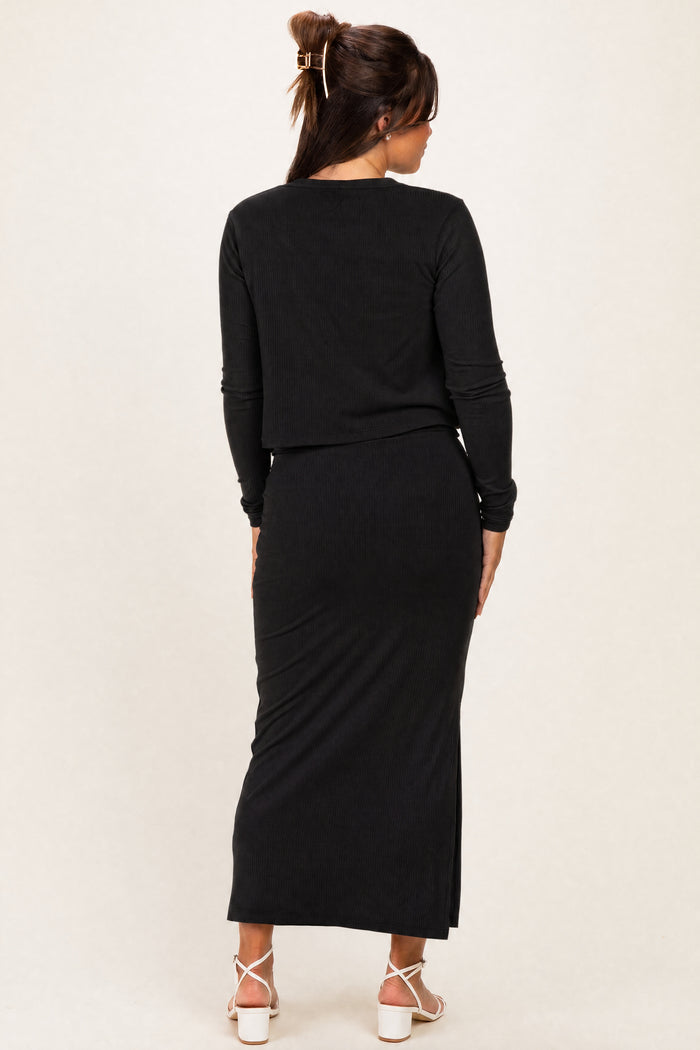 woman wearing a black long sleeve maternity top and matching maxi skirt, showing a pregnant belly from the back