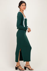 woman wearing a forest green ribbed maxi dress with white trim and side slit, standing sideways against a white background