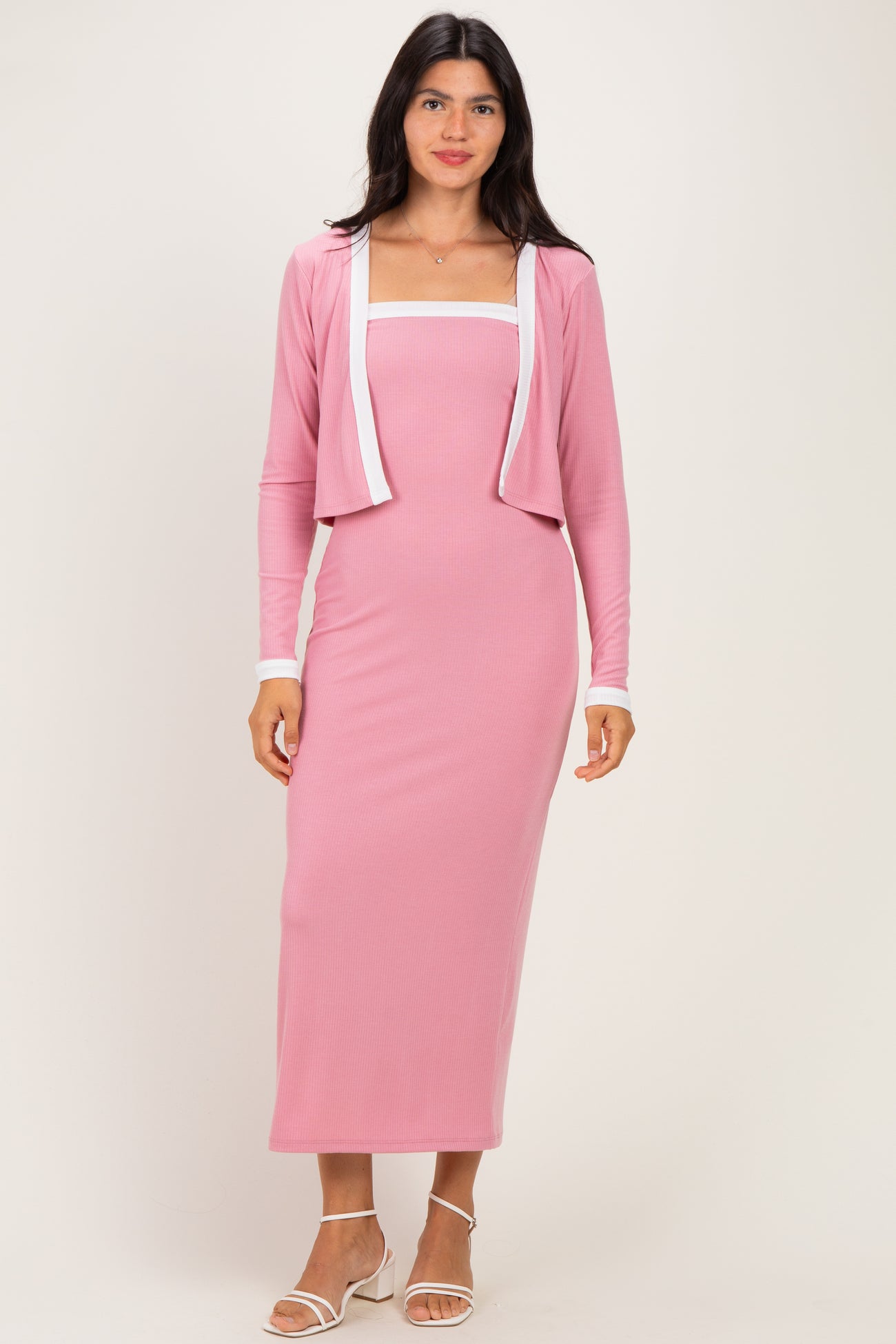woman wearing a pink ribbed maxi dress with a matching cropped cardigan and white trim details