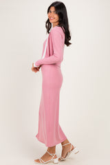 woman wearing a light pink ribbed long sleeve maxi dress with a fitted silhouette and side slit, posed sideways