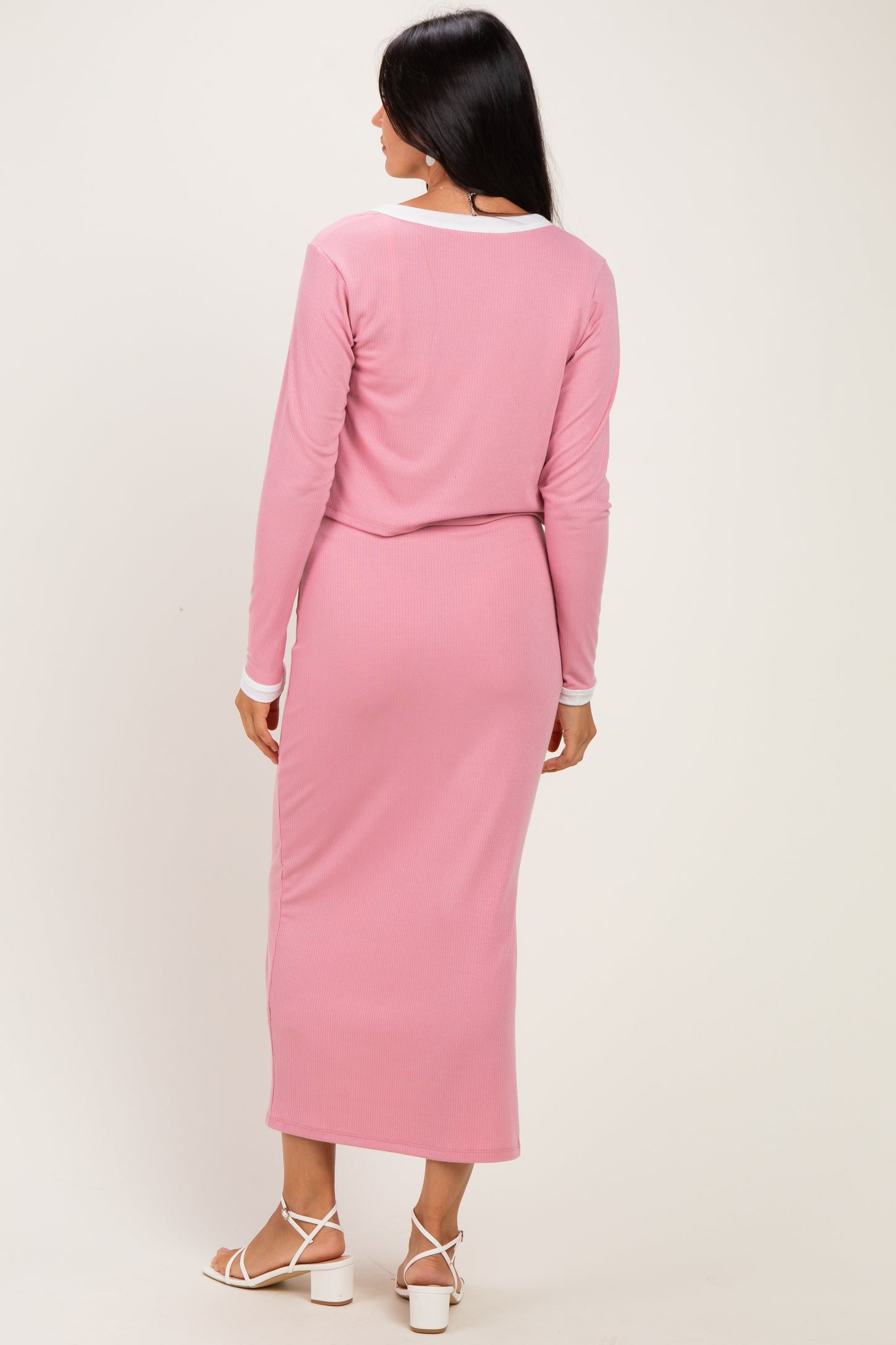 woman wearing a pink ribbed long sleeve top and matching midi skirt, viewed from the back