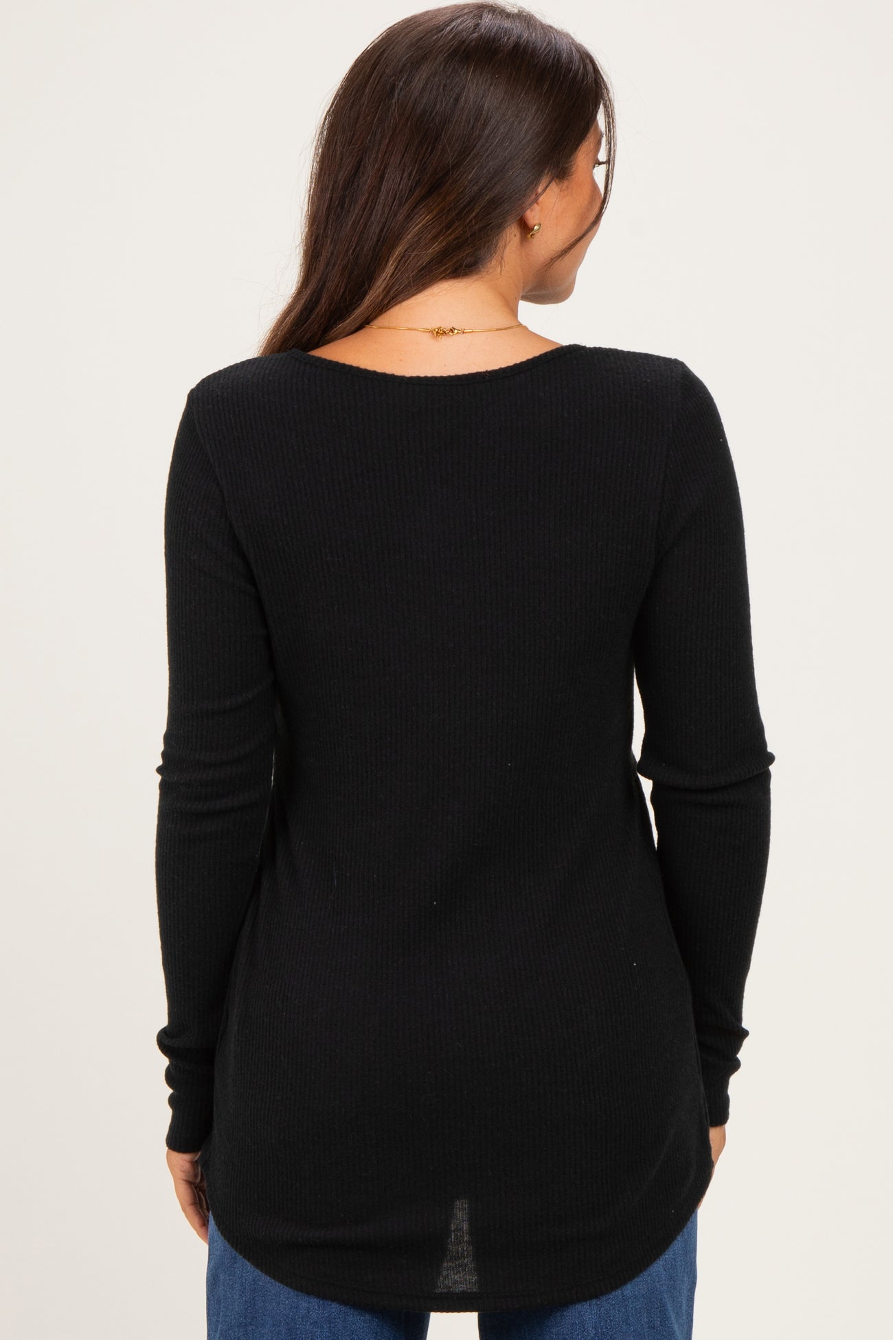 woman wearing a black ribbed maternity top, showing the back view, with long sleeves and a relaxed fit