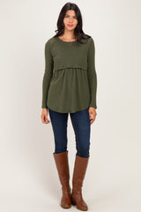 woman wearing an olive green peplum top with long sleeves, paired with dark skinny jeans and tall brown boots