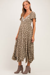 woman wearing a sage green floral maternity dress with short sleeves and a flowy skirt, showing her baby bump