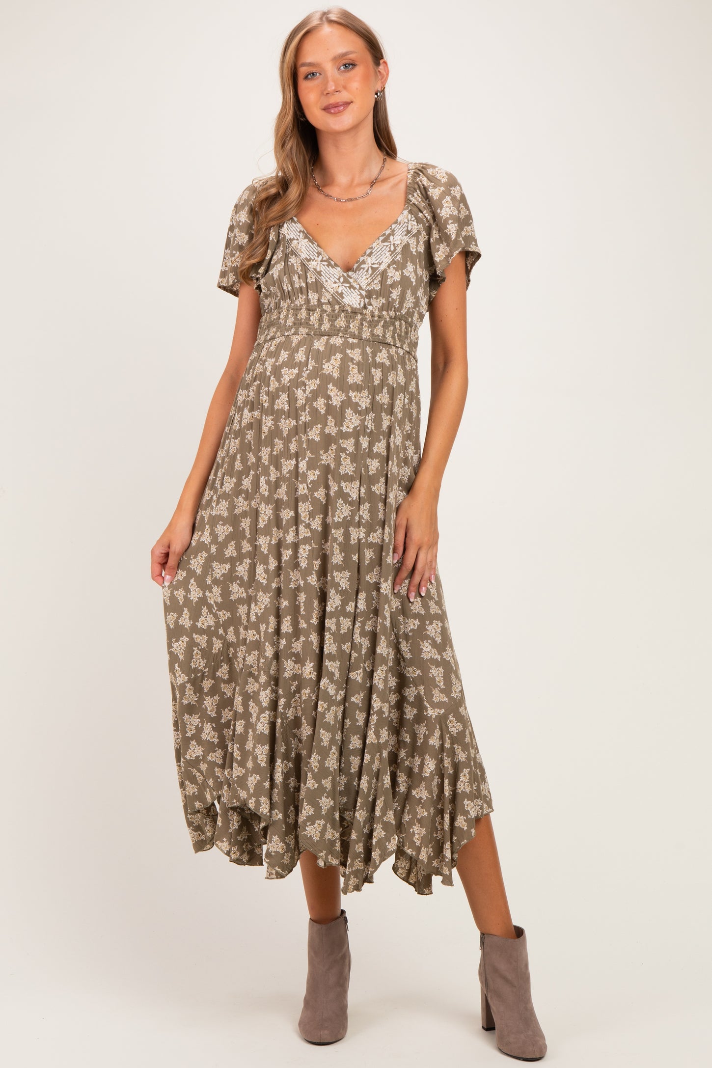 woman wearing a brown floral print maternity dress with a v-neck and short sleeves, showcasing her baby bump