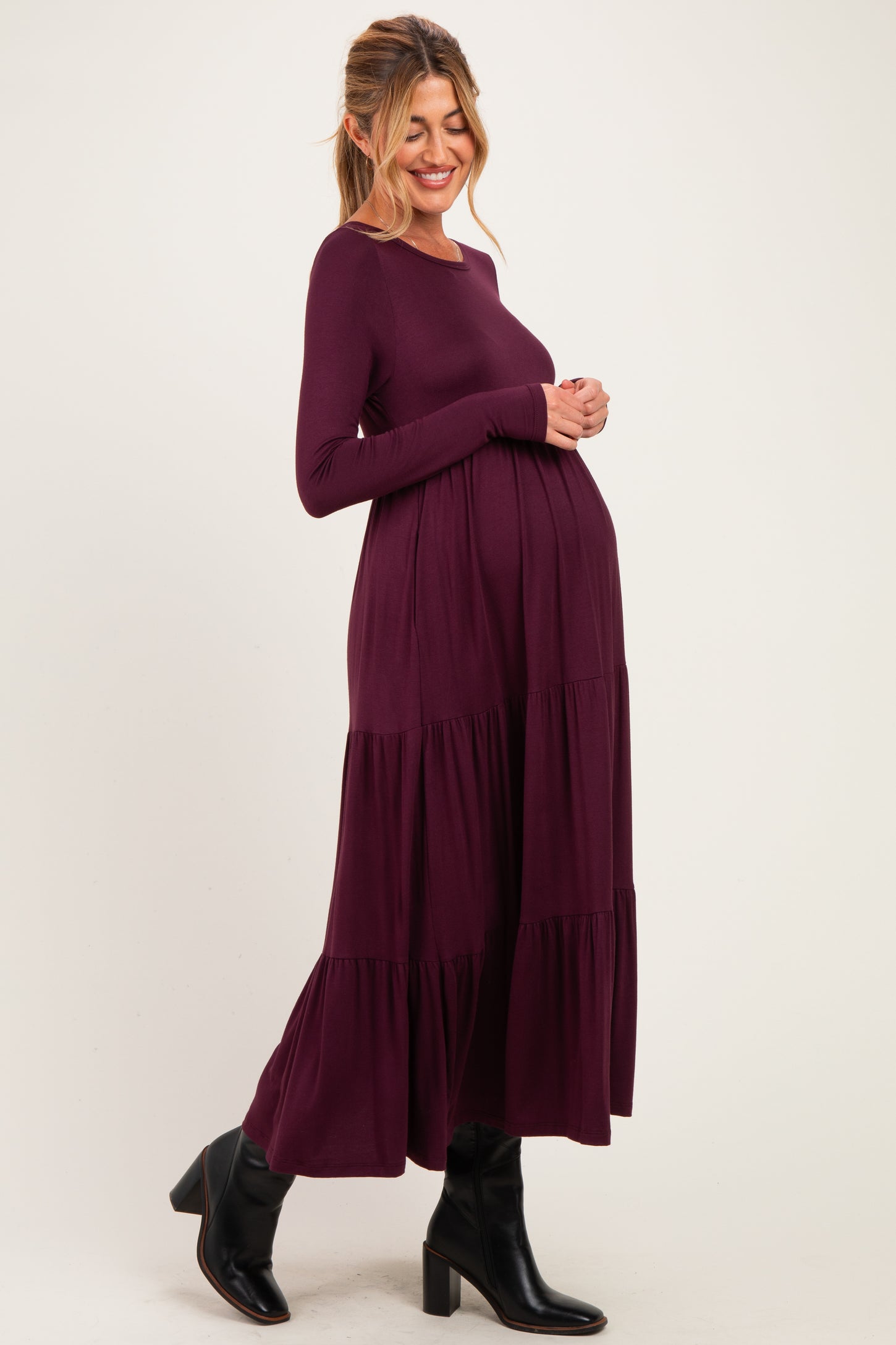 woman wearing a long sleeve maternity dress in deep burgundy with tiered skirt and baby bump visible
