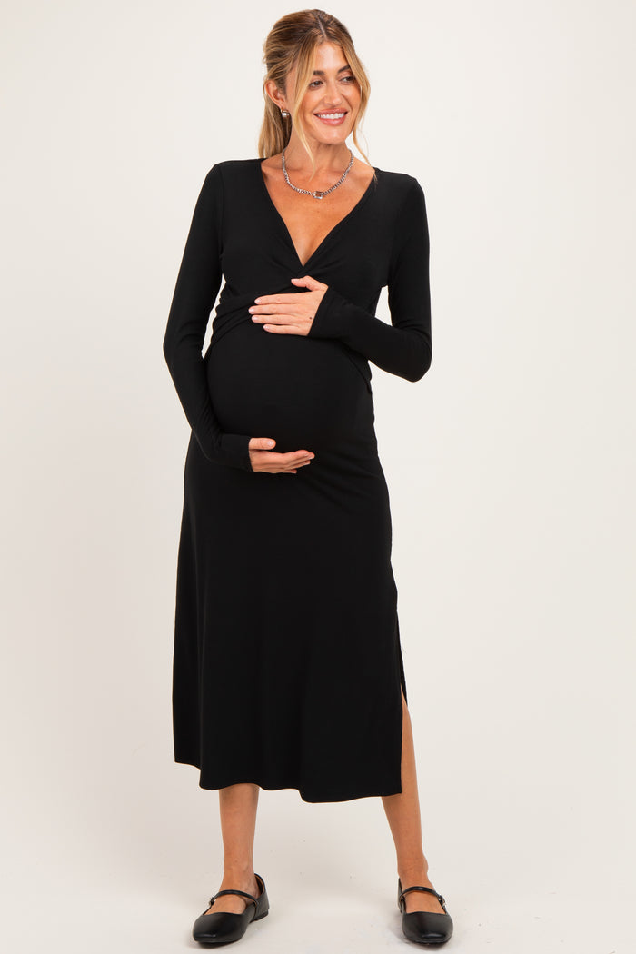 woman wearing a black long sleeve maternity dress with a v-neck and side slit, holding her baby bump