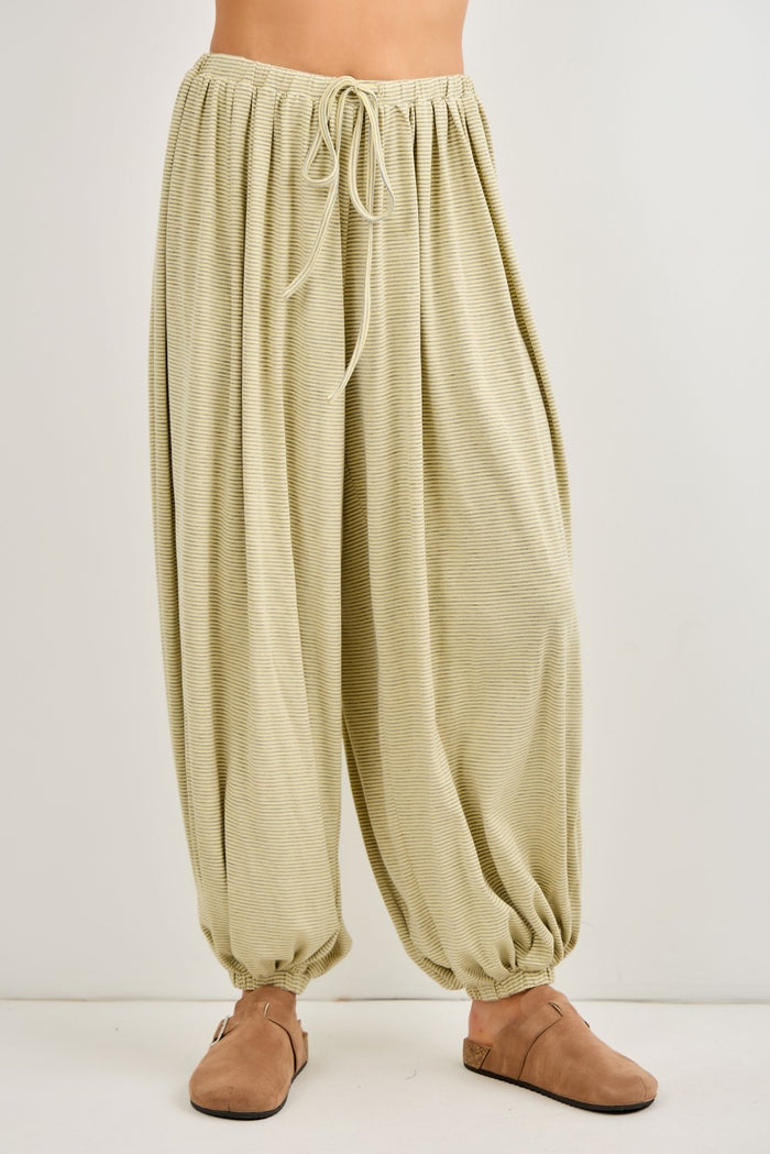 woman wearing light green high-waisted harem pants with a drawstring waist and gathered ankles