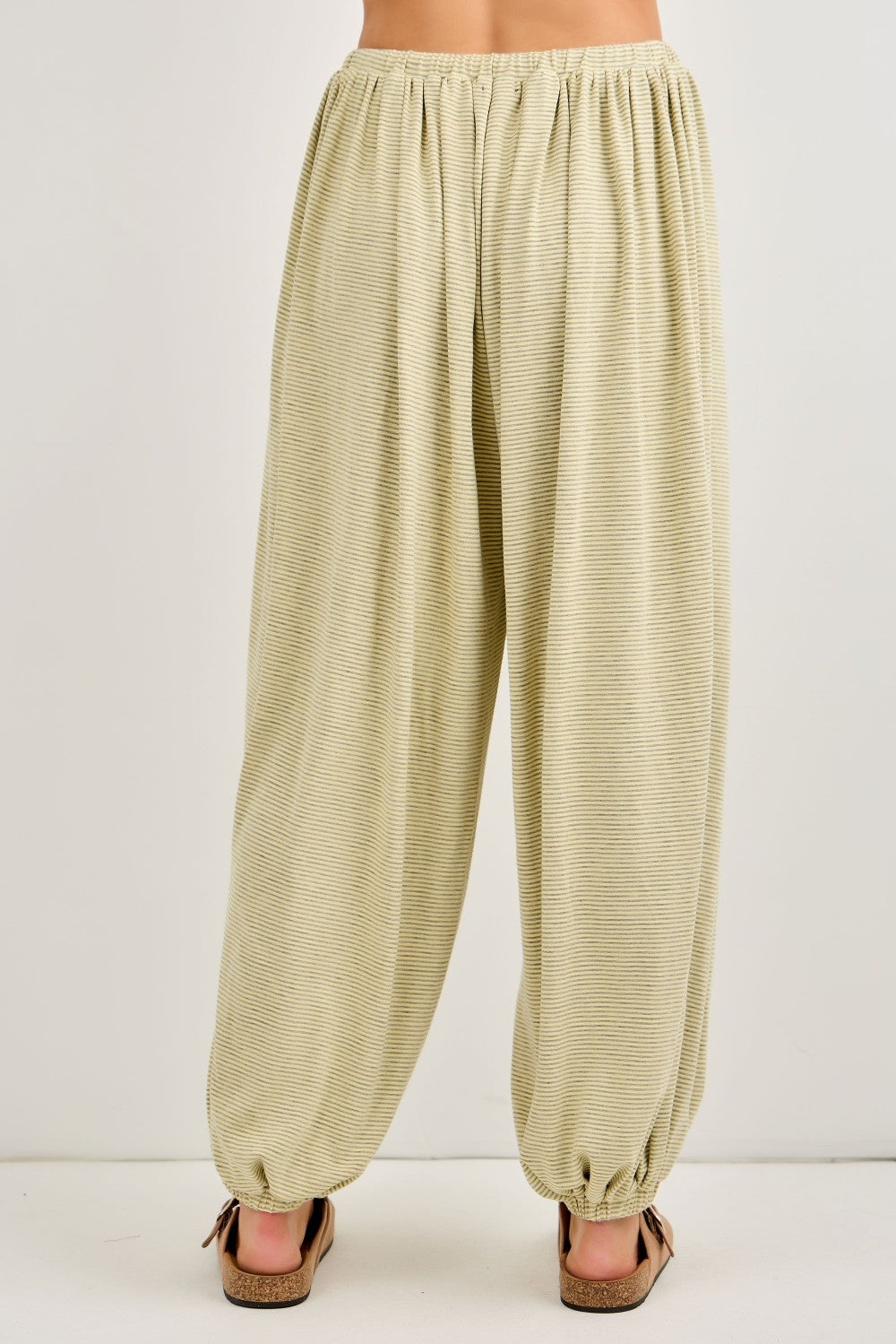 woman wearing light olive green relaxed fit harem pants with an elastic waistband and tapered cuffs