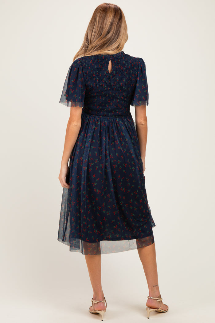 woman wearing a navy blue floral print maternity dress with short flutter sleeves and a smocked bodice