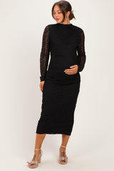 woman wearing a black lace maternity dress with long sleeves and a fitted silhouette, cradling her baby bump