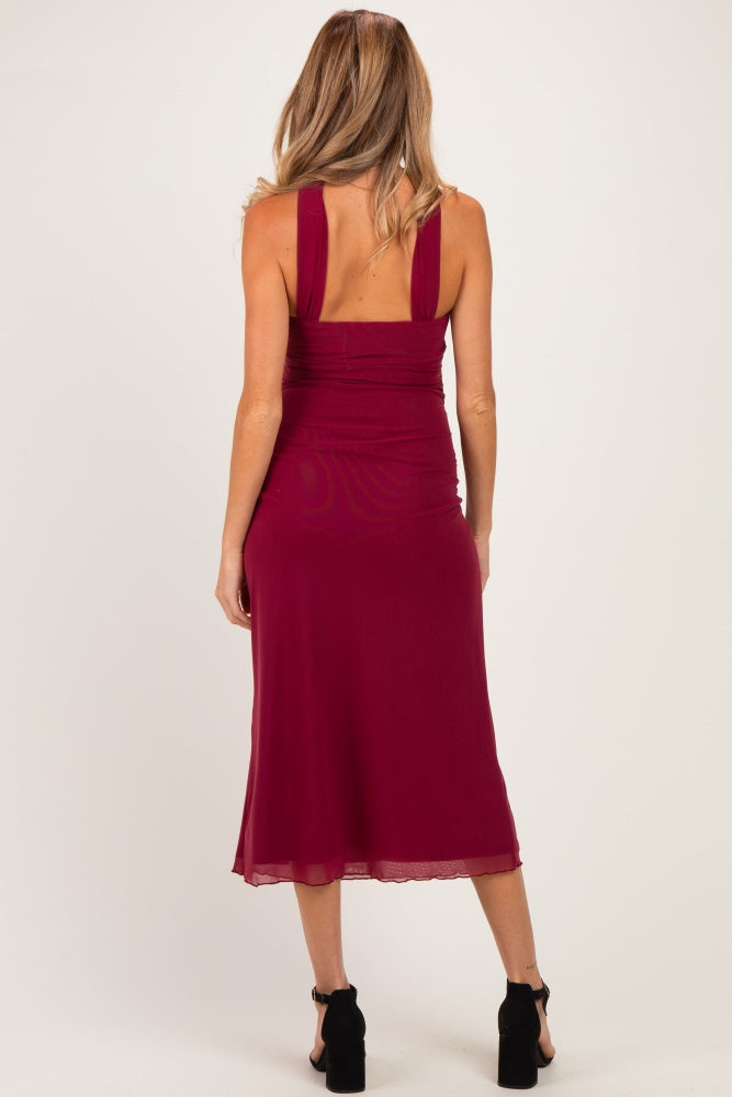 woman wearing a burgundy maternity dress with thick straps and a fitted design, showing off her back