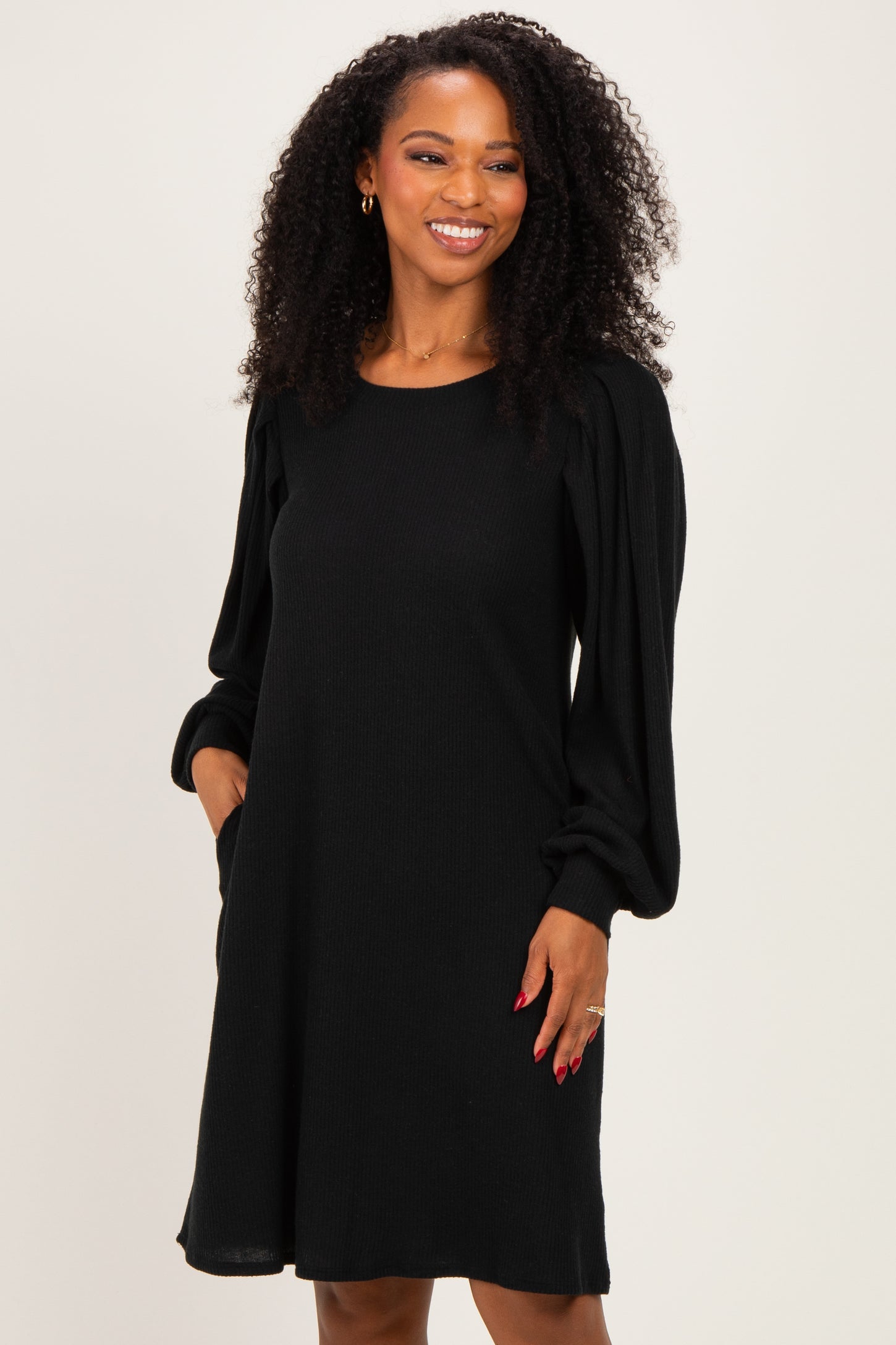 woman wearing a black long sleeve knit dress with puffed sleeves and a relaxed fit