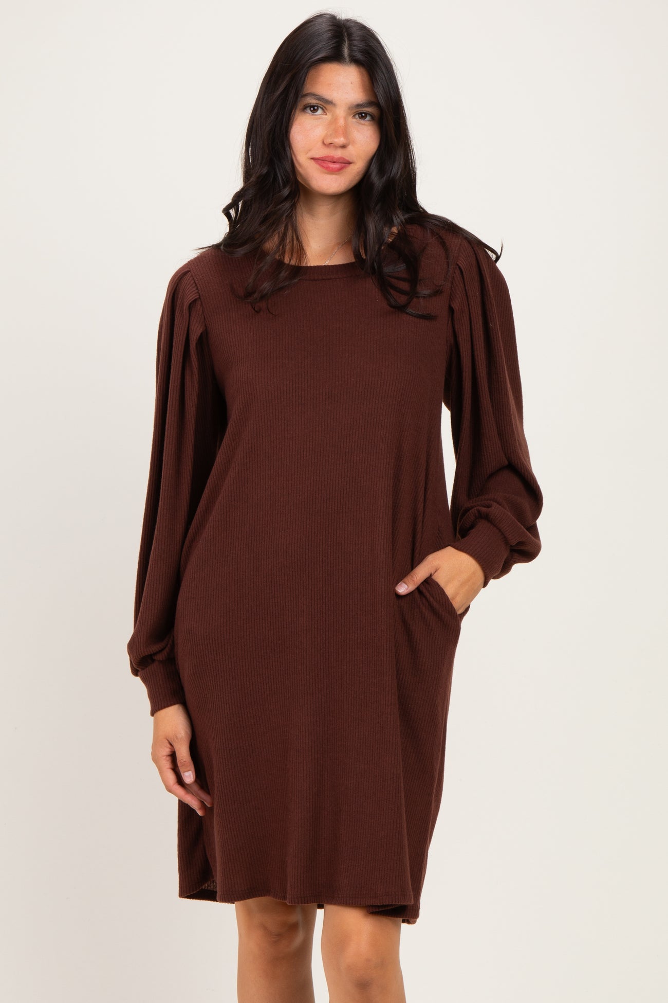 woman wearing a brown long sleeve ribbed dress with puffed sleeves and side pockets