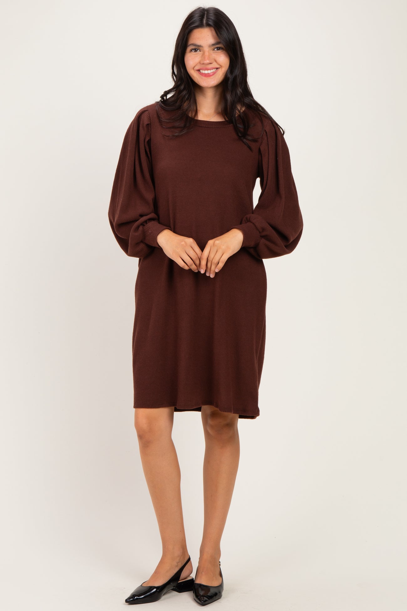woman wearing a brown long sleeve sweater dress with puff sleeves and a relaxed fit