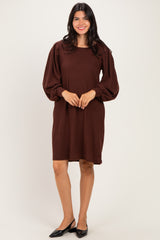 woman wearing a brown long sleeve sweater dress with puff sleeves and a relaxed fit