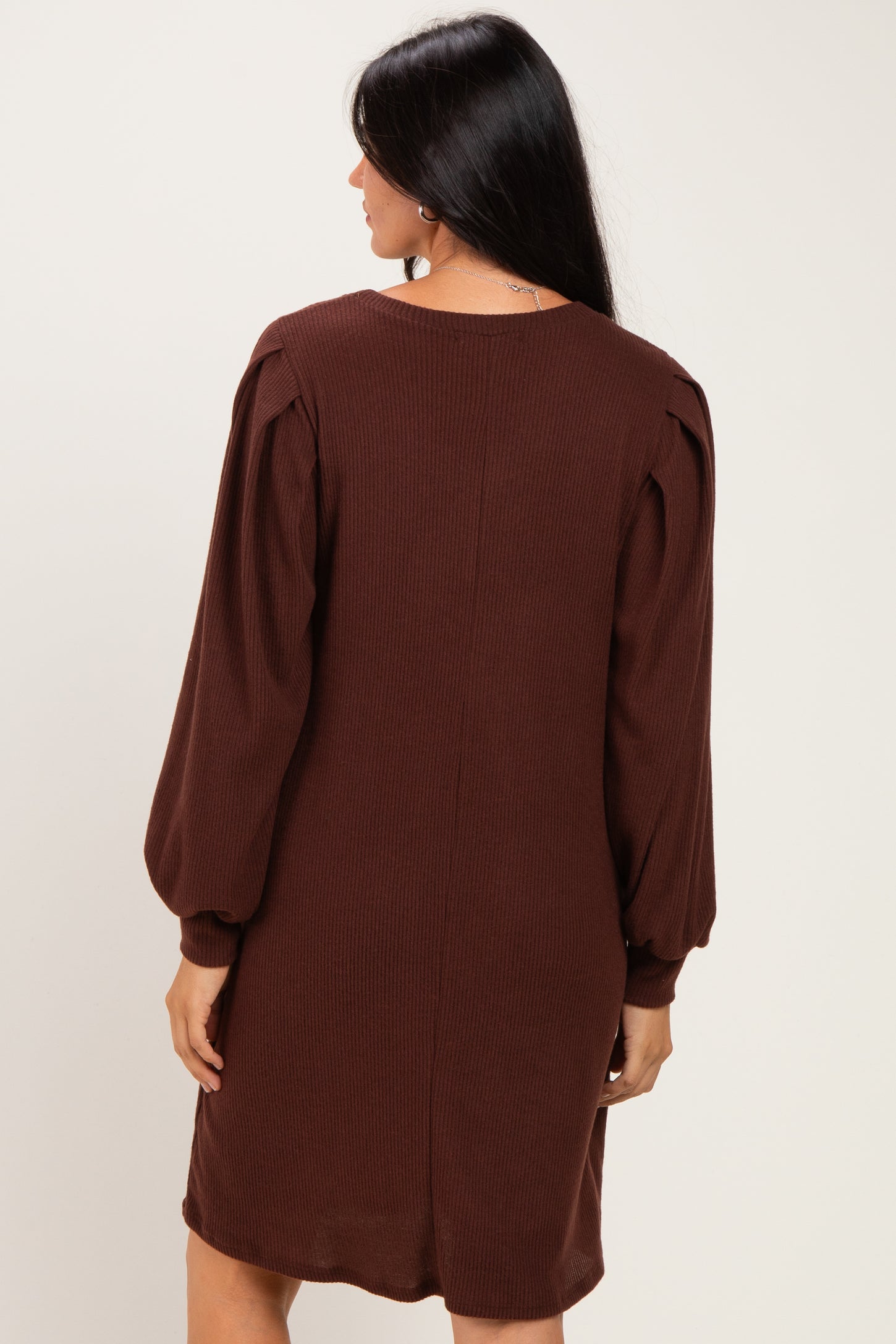 woman wearing a brown ribbed long sleeve dress with puffed sleeves, seen from the back