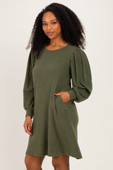 woman wearing an olive green ribbed long sleeve dress with puffed sleeves and side pockets