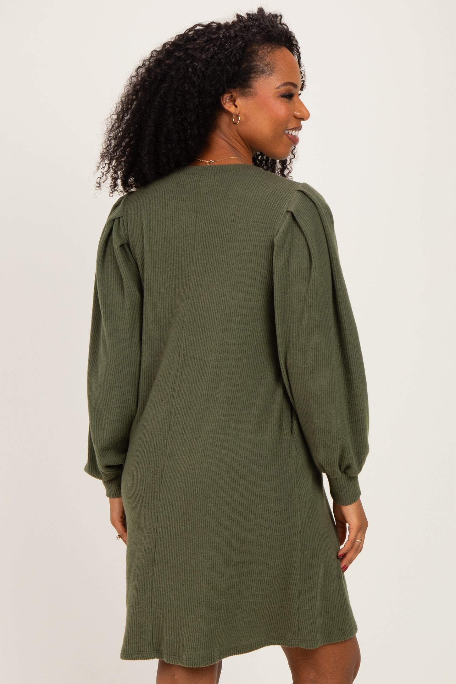 woman wearing a dark green long sleeve sweater dress with puffed sleeves and a relaxed fit
