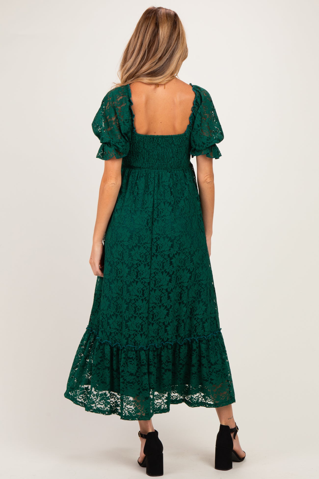 woman wearing a green lace maternity dress with puff sleeves and a tiered skirt, showcasing a smocked back design