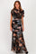 woman wearing a black floral maxi dress with sheer overlay and fitted silhouette