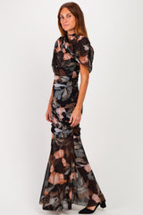 woman wearing a black floral printed evening gown with ruched details and a flared skirt