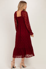 woman wearing a burgundy lace long sleeve midi dress with a ruffled hem and back details