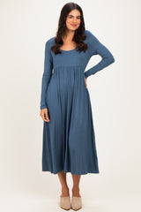 woman wearing a blue long sleeve midi dress with a scoop neckline and a gathered waistline.